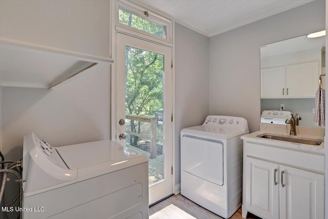 1844 Eastover Dr, Jackson, MS 39211 - laundry area with ornamental molding, washing machine and clothes dryer, a sink, cabinet space, and light wood finished floors