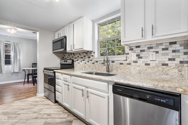 kitchen featuring decorative backsplash, light wood-type flooring, stainless steel appliances, sink, and white cabinetry