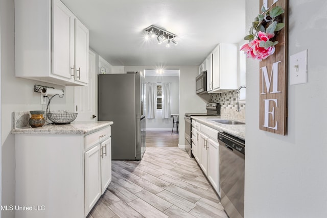 2869 Honduras Dr, Gautier, MS 39553 - kitchen featuring appliances with stainless steel finishes, white cabinetry, decorative backsplash, and light wood finished floors