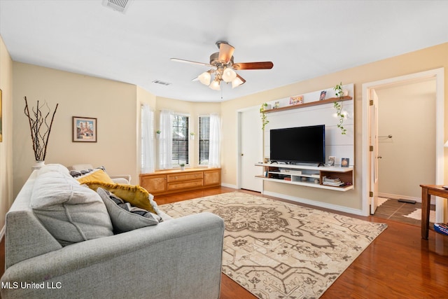 living area featuring visible vents, baseboards, a ceiling fan, and wood finished floors