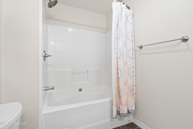 bathroom with baseboards, shower / bath combo with shower curtain, and toilet