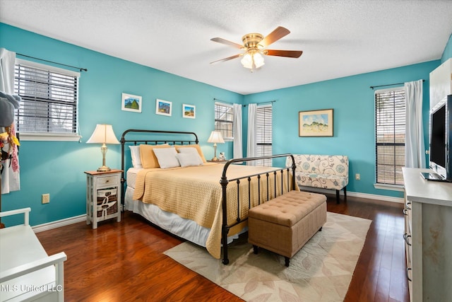 bedroom with multiple windows, a textured ceiling, and wood finished floors