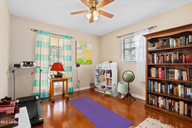 exercise area featuring a healthy amount of sunlight, wood finished floors, and a ceiling fan