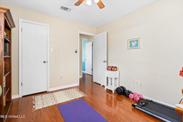 exercise area with ceiling fan, visible vents, baseboards, and wood finished floors