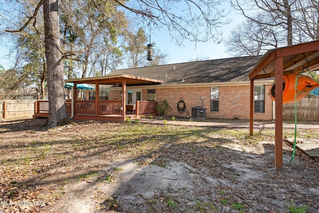 back of house featuring brick siding, central air condition unit, a deck, and fence