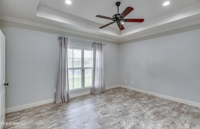 empty room with baseboards, a tray ceiling, a ceiling fan, and ornamental molding
