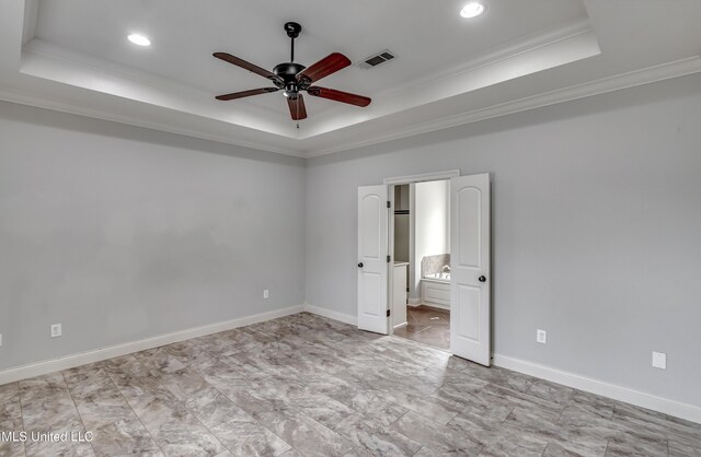 unfurnished bedroom featuring a tray ceiling, baseboards, visible vents, and crown molding