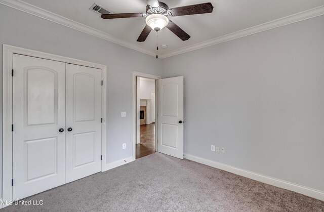 unfurnished bedroom with crown molding, a closet, carpet floors, baseboards, and visible vents