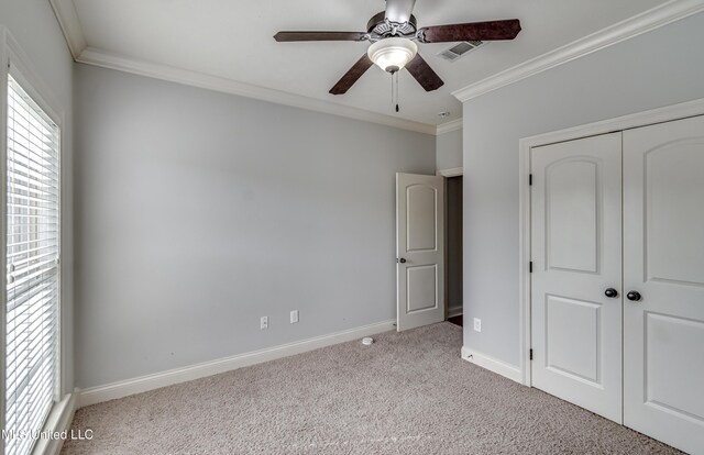 unfurnished bedroom with baseboards, visible vents, crown molding, and carpet