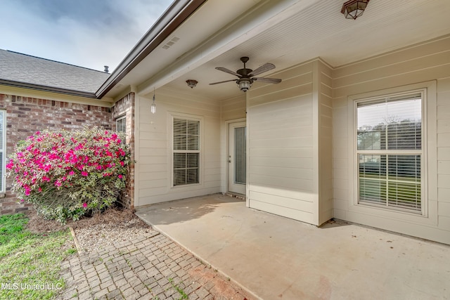entrance to property with a patio area, roof with shingles, brick siding, visible vents, and ceiling fan