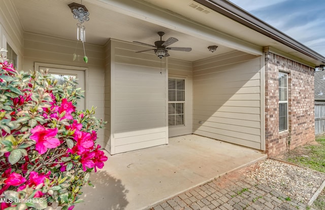 property entrance with brick siding, visible vents, a ceiling fan, and a patio area