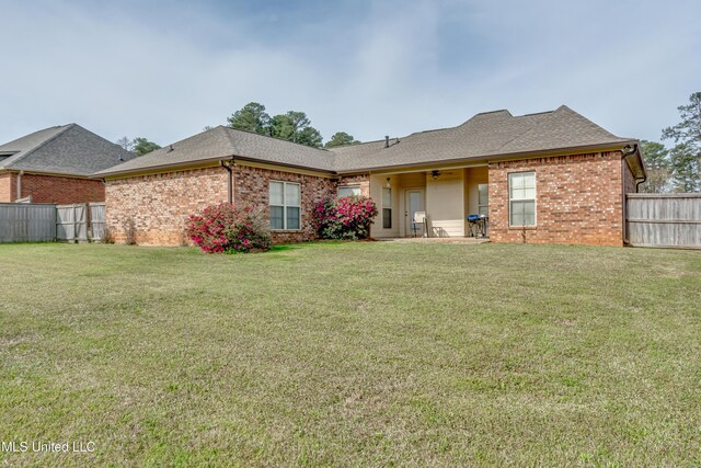 view of front of property with a shingled roof, a front yard, fence, and brick siding