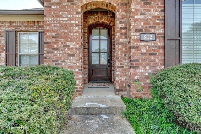 doorway to property featuring brick siding