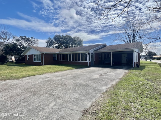 ranch-style house with brick siding, concrete driveway, a front yard, a sunroom, and a carport