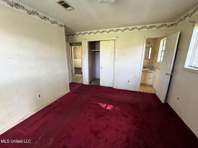 208 Cedar Dr, Diberville, MS 39540 - unfurnished bedroom featuring a closet, carpet flooring, ensuite bathroom, and a textured ceiling