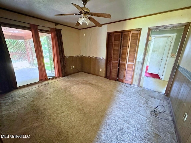 208 Cedar Dr, Diberville, MS 39540 - unfurnished bedroom featuring carpet floors, wooden walls, a wainscoted wall, crown molding, and a textured ceiling