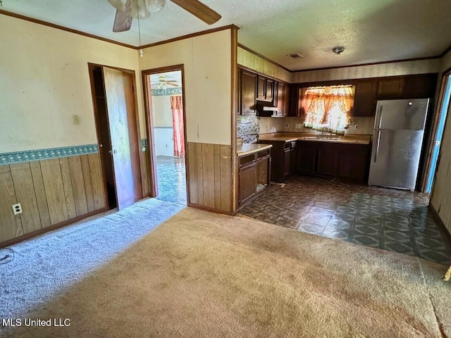 208 Cedar Dr, Diberville, MS 39540 - kitchen with freestanding refrigerator, crown molding, wainscoting, a ceiling fan, and wooden walls