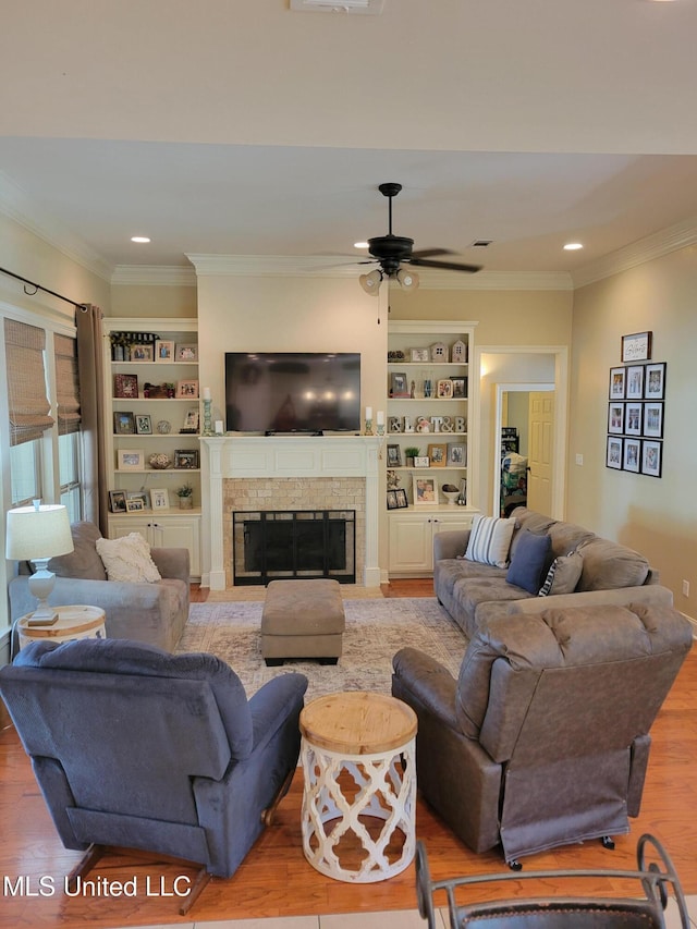 living room with built in shelves, ceiling fan, crown molding, and wood-type flooring