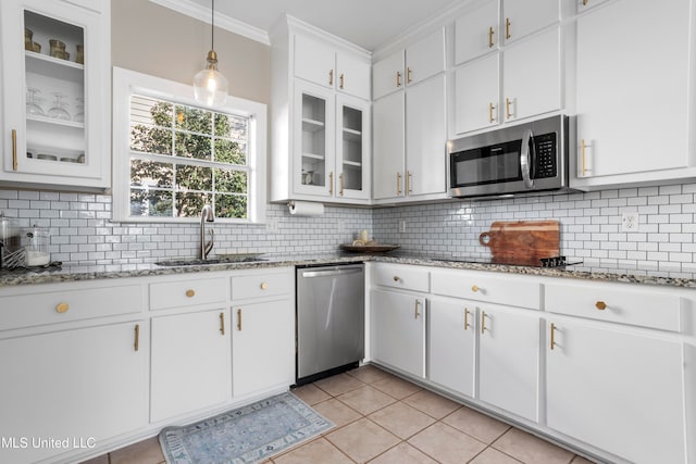 kitchen featuring white cabinets, decorative backsplash, appliances with stainless steel finishes, light tile patterned flooring, and sink