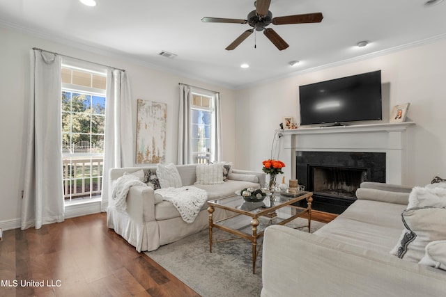 living room with dark wood-type flooring, crown molding, and ceiling fan