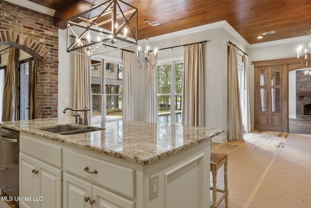 kitchen with a sink, an island with sink, an inviting chandelier, light stone countertops, and wood ceiling