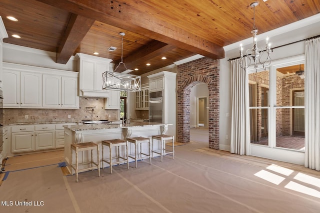 kitchen with arched walkways, a notable chandelier, beam ceiling, and wooden ceiling