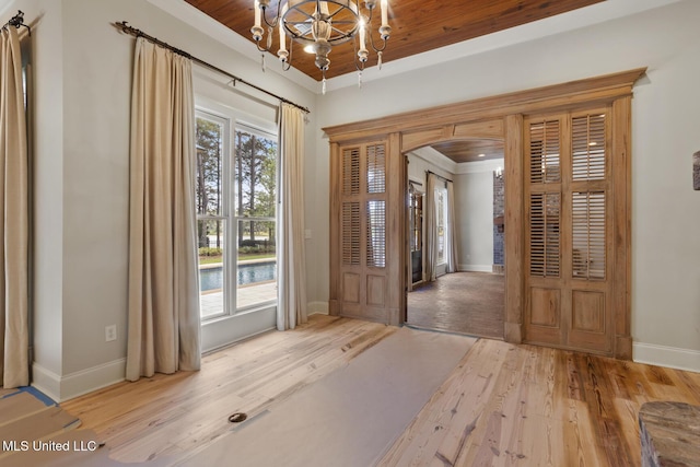 foyer entrance with an inviting chandelier, arched walkways, baseboards, and wood finished floors