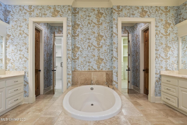 bathroom featuring vanity, stone finish flooring, baseboards, a bath, and wallpapered walls