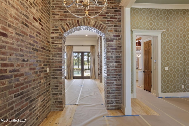 corridor with baseboards, a notable chandelier, crown molding, and wood finished floors