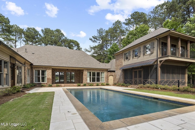 back of house with a lawn, brick siding, an outdoor pool, a sunroom, and roof with shingles