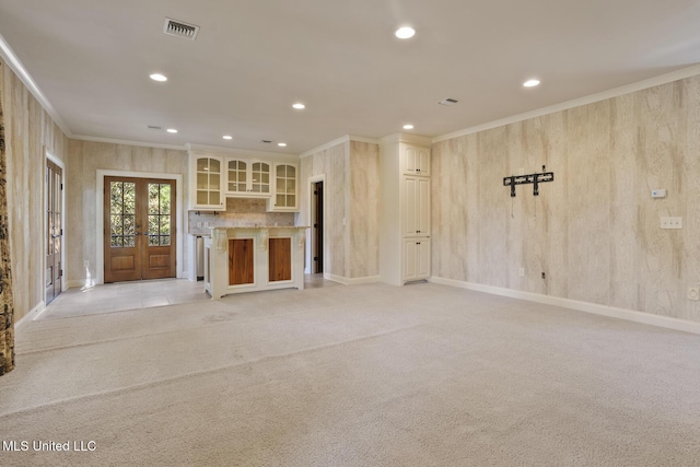 unfurnished living room with french doors, light colored carpet, visible vents, recessed lighting, and crown molding