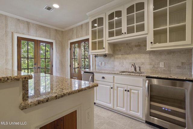 kitchen featuring french doors, visible vents, decorative backsplash, glass insert cabinets, and beverage cooler