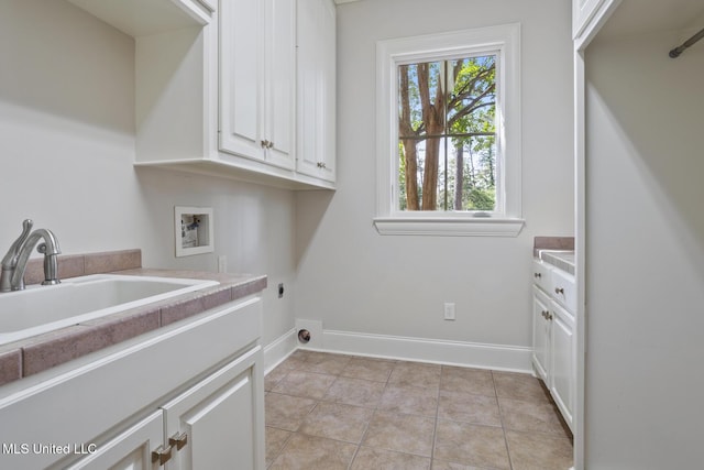 washroom with baseboards, a sink, washer hookup, hookup for an electric dryer, and cabinet space
