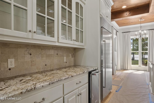 bar featuring pendant lighting, stainless steel built in refrigerator, an inviting chandelier, wood ceiling, and decorative backsplash