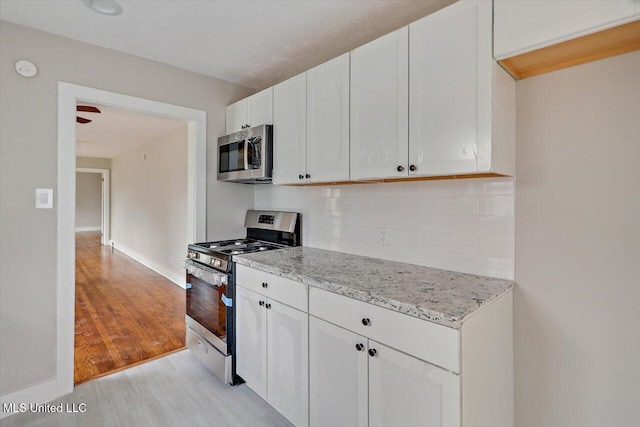 127 Autumn Dr, Vicksburg, MS 39180 - kitchen with stainless steel appliances, backsplash, white cabinetry, light stone countertops, and light wood-type flooring