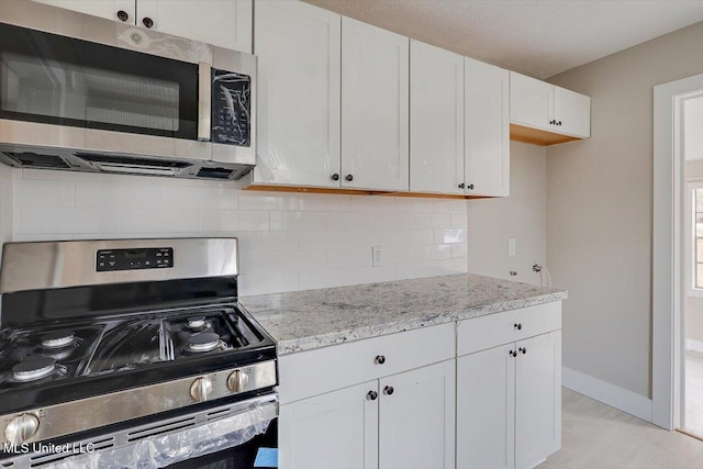 127 Autumn Dr, Vicksburg, MS 39180 - kitchen with tasteful backsplash, baseboards, white cabinets, appliances with stainless steel finishes, and light stone countertops