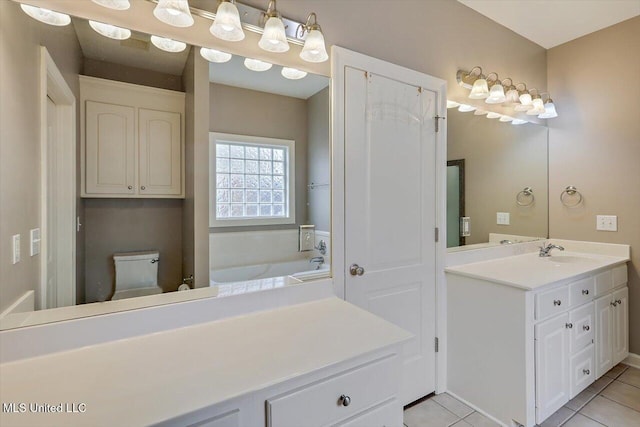 bathroom featuring tile patterned flooring, vanity, a bathing tub, and toilet