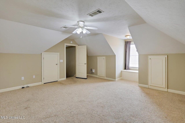 additional living space with ceiling fan, light colored carpet, lofted ceiling, and a textured ceiling