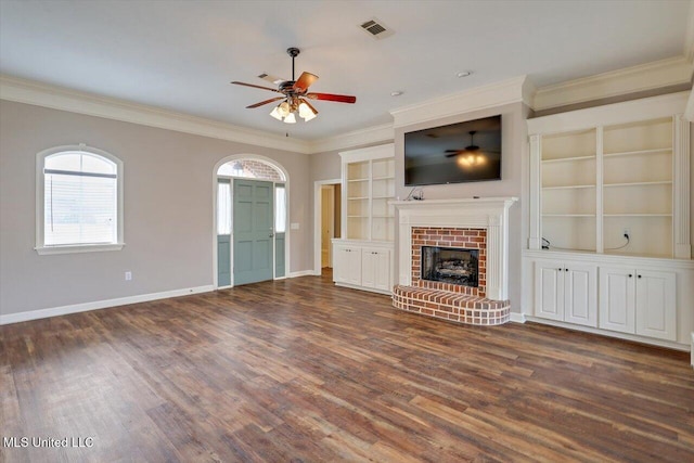 unfurnished living room featuring dark wood-type flooring, ceiling fan, crown molding, and a brick fireplace