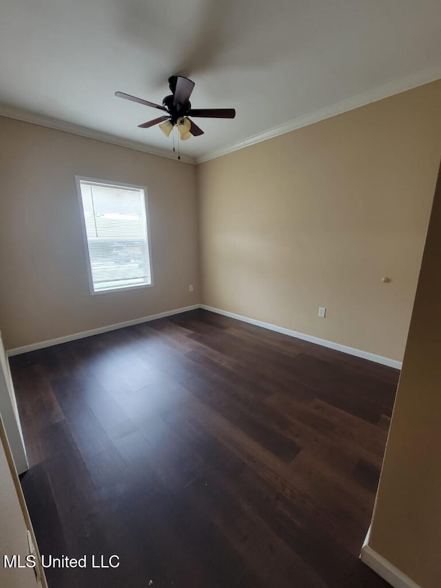 spare room featuring crown molding, ceiling fan, baseboards, and dark wood-type flooring