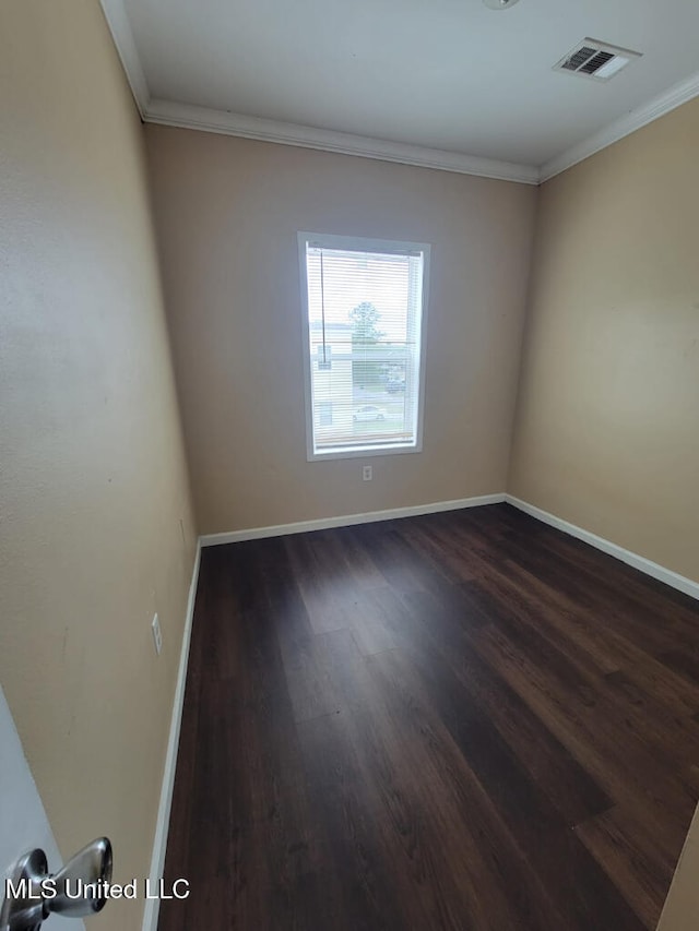 unfurnished room with visible vents, ornamental molding, dark wood finished floors, and baseboards