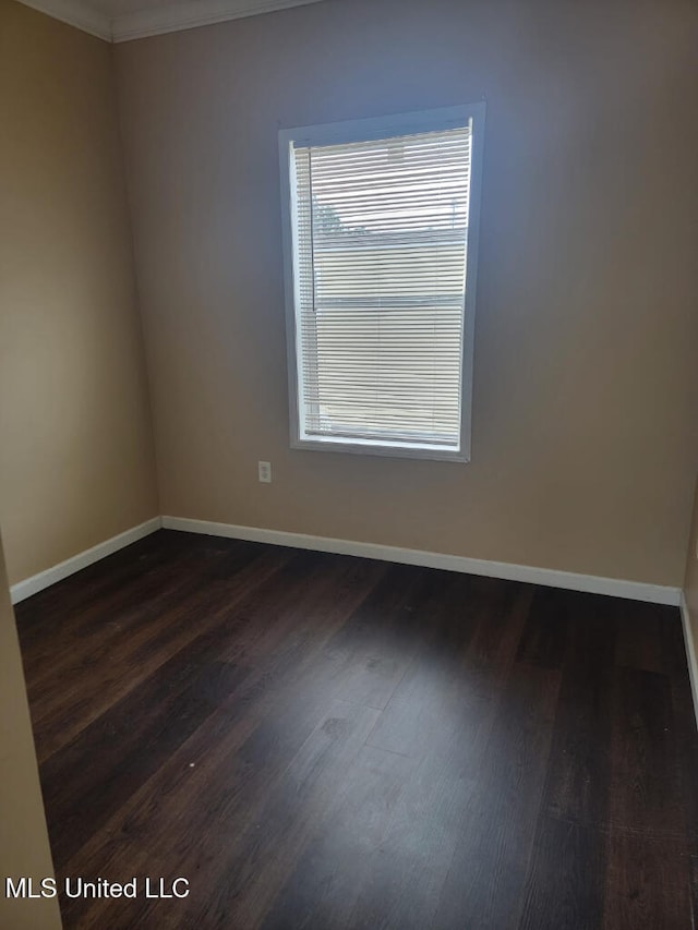 unfurnished room with baseboards, ornamental molding, and dark wood-style floors