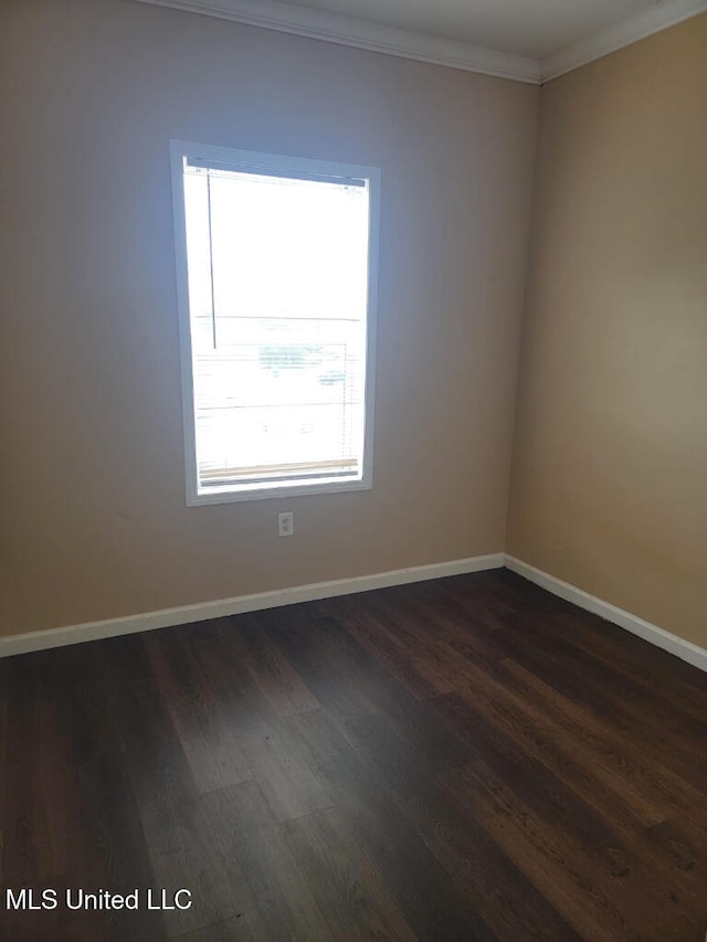 empty room with dark wood-type flooring, ornamental molding, and baseboards