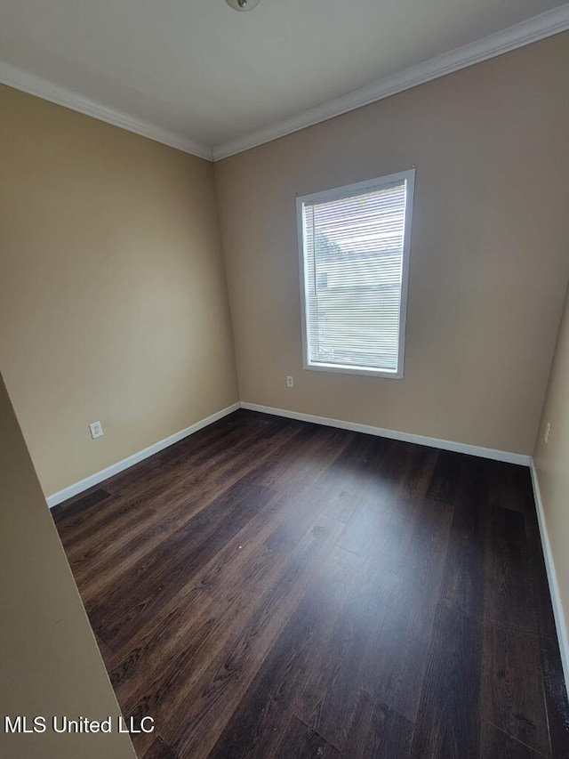 spare room featuring baseboards, dark wood finished floors, and crown molding