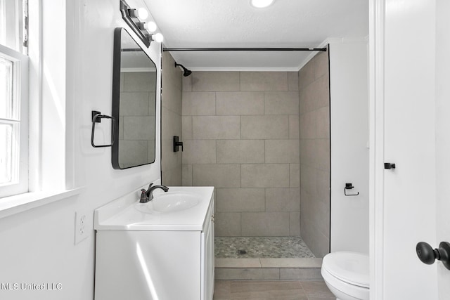 bathroom with vanity, toilet, and a tile shower