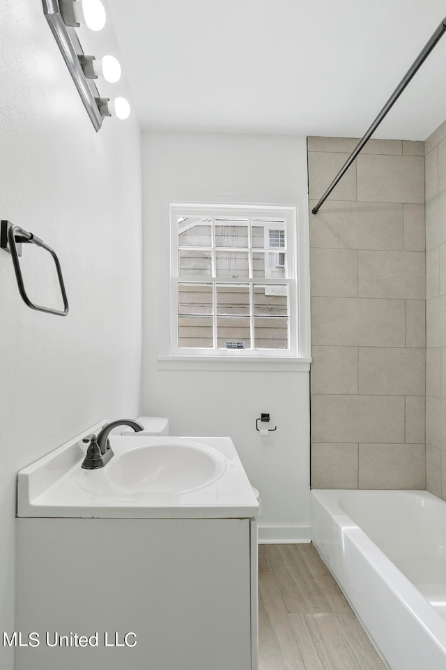 full bathroom featuring vanity, toilet, wood-type flooring, and tiled shower / bath