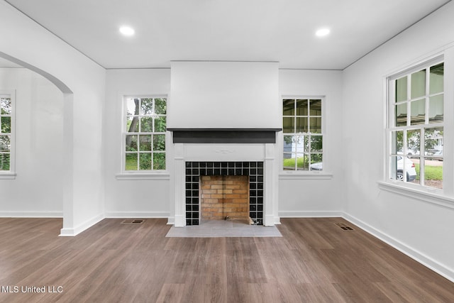 unfurnished living room with a fireplace, hardwood / wood-style flooring, and a healthy amount of sunlight