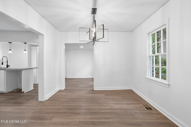 unfurnished dining area featuring an inviting chandelier, sink, and dark hardwood / wood-style floors