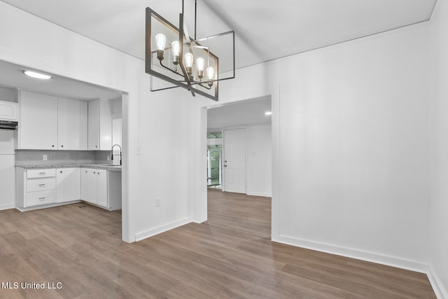 kitchen featuring light hardwood / wood-style flooring, sink, white cabinetry, decorative light fixtures, and an inviting chandelier