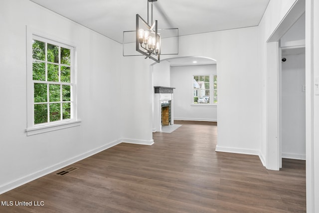 unfurnished dining area featuring a notable chandelier and dark hardwood / wood-style flooring